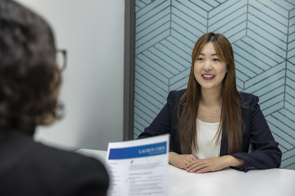Confident, Beautiful Asian Woman in suit is smiling during job interview in office environment